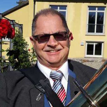Herbert Rotzinger, Material und Instrumentenwart. Mann mit Brille in der Uniform des Musikvereins Rheinheim, vor einem gelben Gebäude.